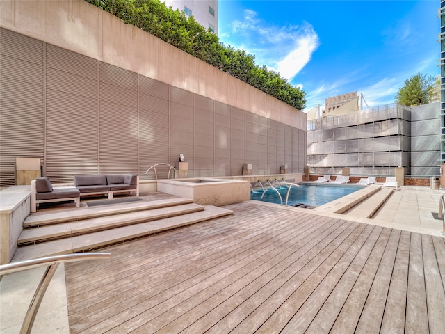 view of pool with an outdoor living space, a deck, and pool water feature