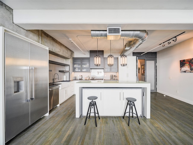 kitchen with dark hardwood / wood-style flooring, decorative light fixtures, appliances with stainless steel finishes, a kitchen island, and white cabinetry