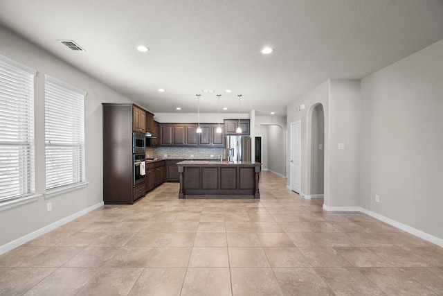 kitchen with a center island, light tile patterned flooring, stainless steel appliances, dark brown cabinetry, and decorative light fixtures