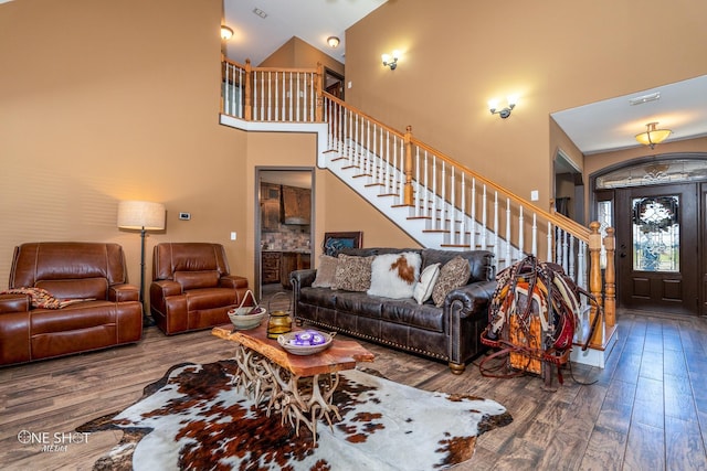 living room with dark wood-type flooring and a towering ceiling