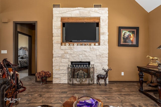 living room featuring dark hardwood / wood-style flooring, a stone fireplace, and lofted ceiling