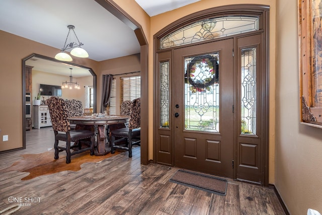 foyer entrance with plenty of natural light, a chandelier, and dark hardwood / wood-style floors