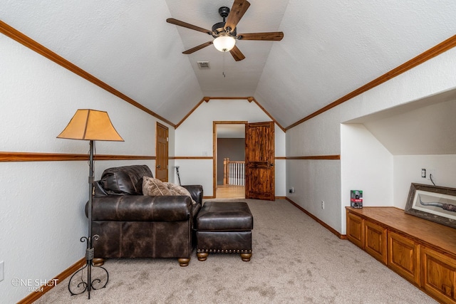 living area with ceiling fan, ornamental molding, vaulted ceiling, and light carpet