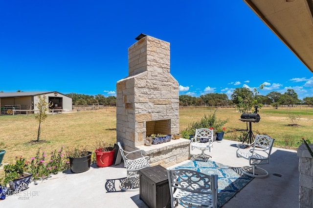 view of patio featuring an outdoor stone fireplace and a rural view