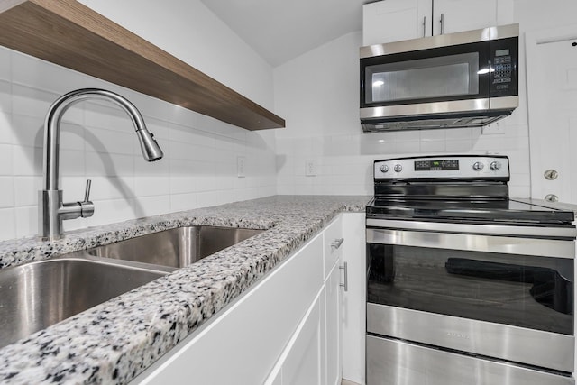 kitchen with white cabinetry, sink, light stone counters, backsplash, and appliances with stainless steel finishes