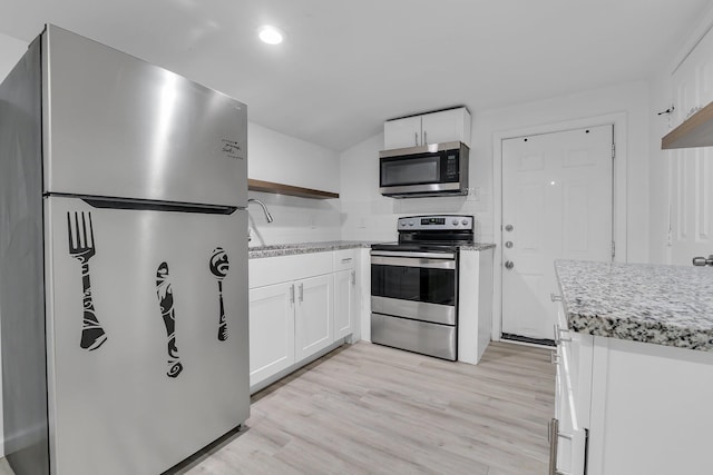 kitchen with appliances with stainless steel finishes, light hardwood / wood-style flooring, white cabinetry, and sink