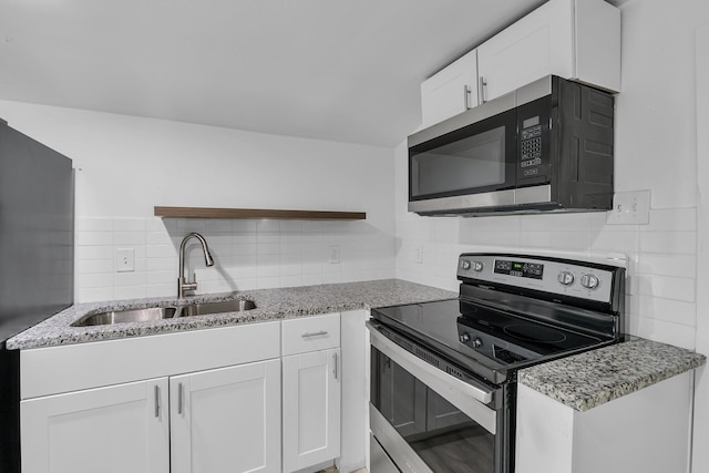 kitchen with light stone countertops, sink, tasteful backsplash, white cabinets, and appliances with stainless steel finishes