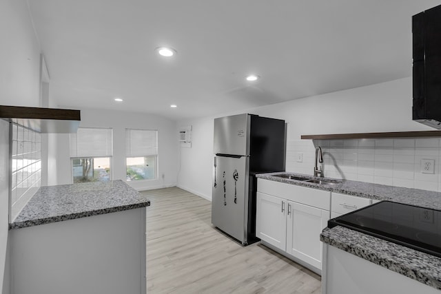 kitchen featuring sink, backsplash, stainless steel fridge, light hardwood / wood-style floors, and white cabinets