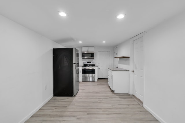 kitchen featuring light stone countertops, light hardwood / wood-style flooring, white cabinets, and appliances with stainless steel finishes