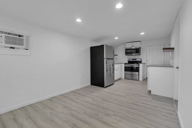 kitchen with white cabinets, a wall mounted air conditioner, stainless steel appliances, and light hardwood / wood-style flooring