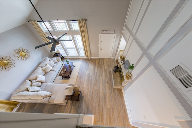 living room with ceiling fan, high vaulted ceiling, and wood-type flooring