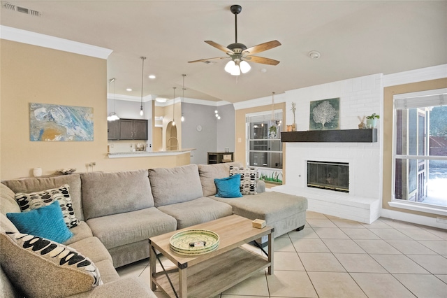 living room with ceiling fan, a wealth of natural light, crown molding, and a brick fireplace