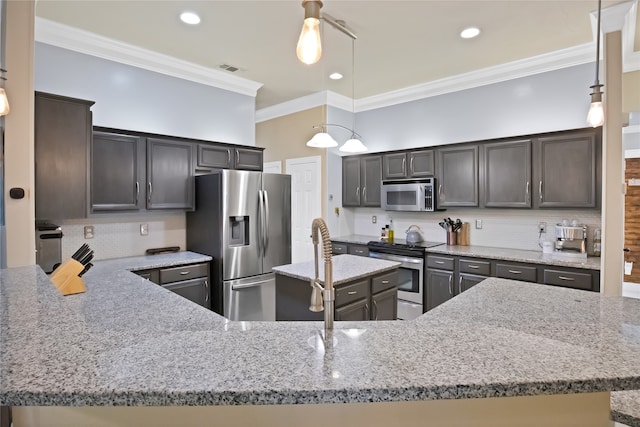 kitchen with appliances with stainless steel finishes, decorative light fixtures, decorative backsplash, light stone counters, and crown molding