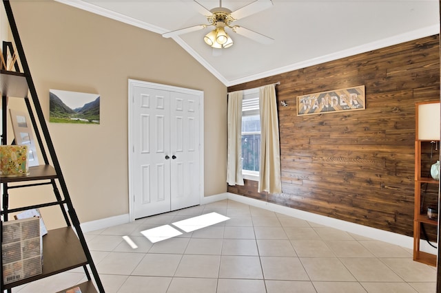 tiled foyer with ceiling fan, wooden walls, vaulted ceiling, and ornamental molding