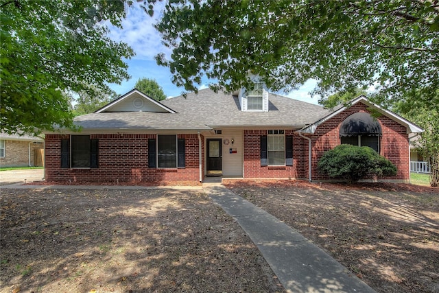 view of front of property featuring brick siding and roof with shingles