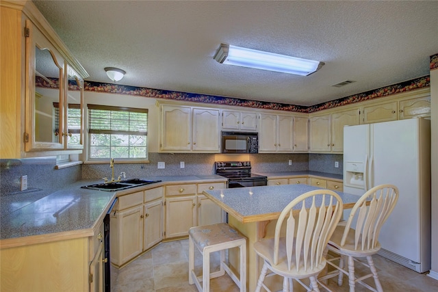 kitchen featuring a breakfast bar area, tasteful backsplash, visible vents, a sink, and black appliances