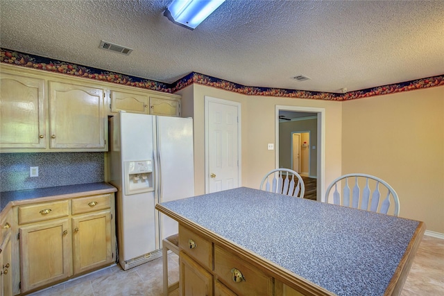 kitchen with white refrigerator with ice dispenser, dark countertops, visible vents, a kitchen island, and a textured ceiling