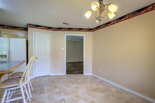 interior space featuring white refrigerator with ice dispenser, light hardwood / wood-style flooring, a textured ceiling, and a chandelier