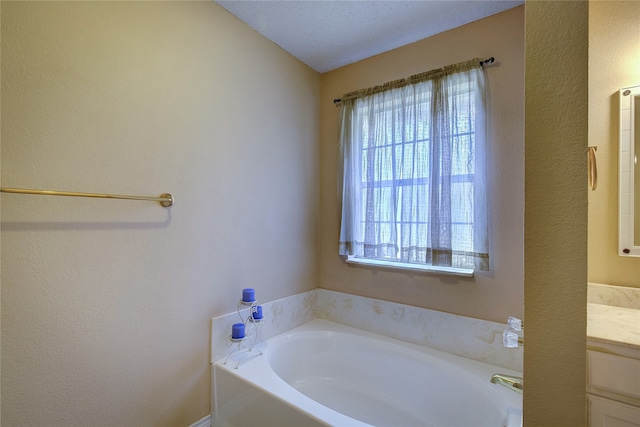 bathroom featuring a bath, a textured ceiling, and vanity