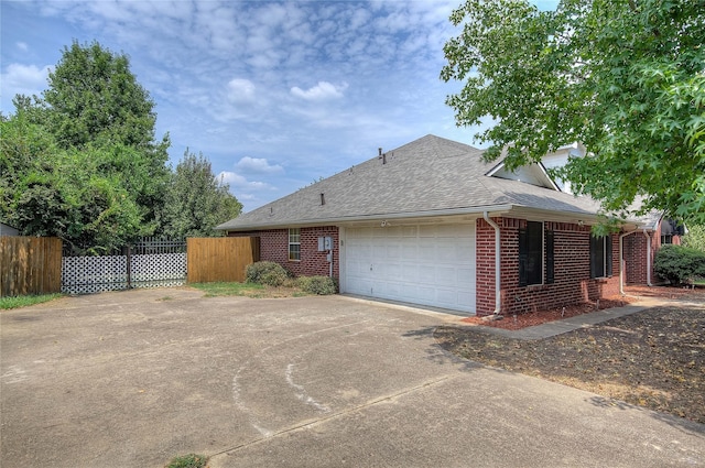 view of front of home featuring a garage, brick siding, a shingled roof, fence, and driveway