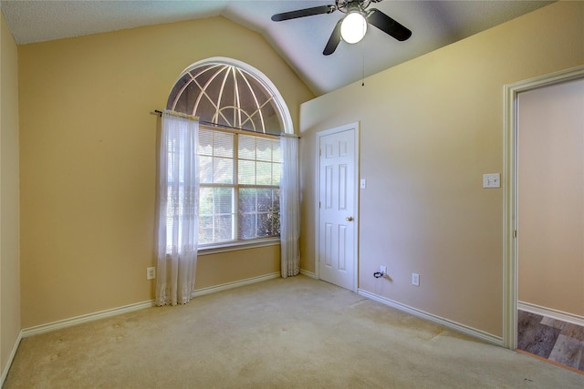 unfurnished room featuring a ceiling fan, lofted ceiling, baseboards, and carpet