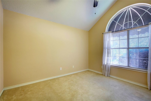 empty room with a ceiling fan, light carpet, vaulted ceiling, and baseboards