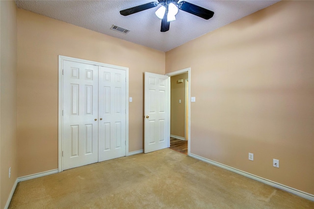 unfurnished bedroom featuring carpet floors, a closet, visible vents, a textured ceiling, and baseboards