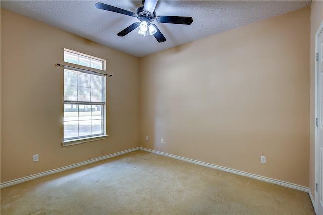 carpeted empty room with a ceiling fan, baseboards, and a textured ceiling