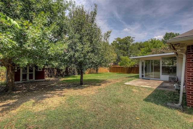 view of yard with an outbuilding, a storage shed, a sunroom, a patio area, and fence