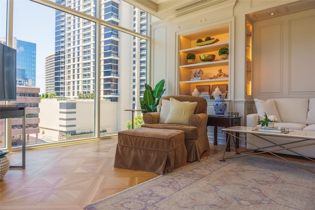 living area featuring a wall of windows, plenty of natural light, light parquet flooring, and built in shelves