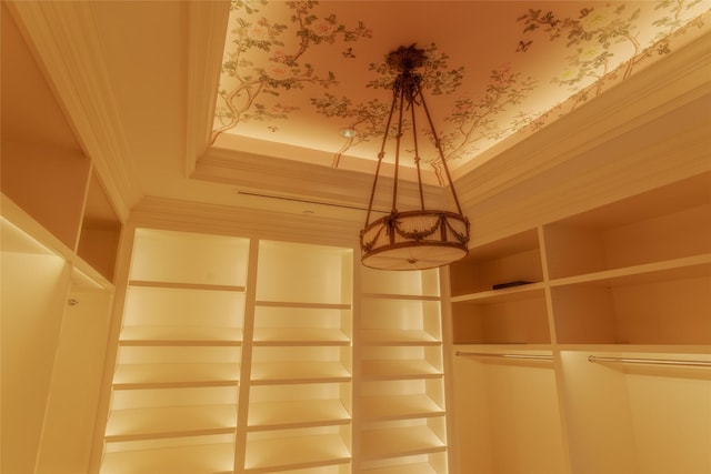 interior details with crown molding, a tray ceiling, and wallpapered walls