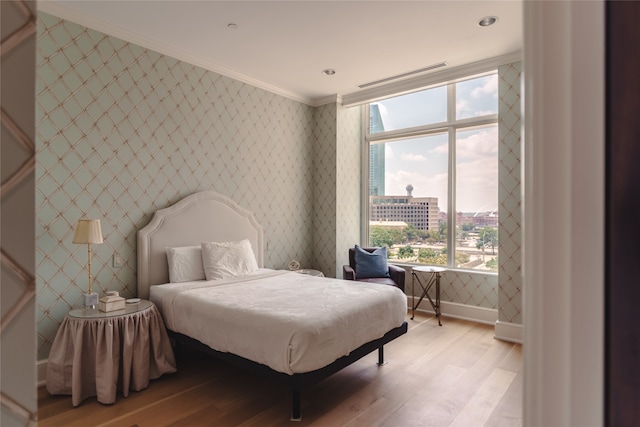 bedroom with light hardwood / wood-style floors and ornamental molding