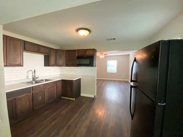 kitchen featuring dark wood-type flooring, sink, decorative backsplash, and black appliances