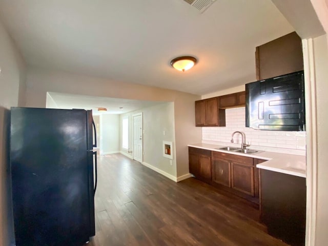 kitchen with black fridge, dark wood-type flooring, sink, and decorative backsplash