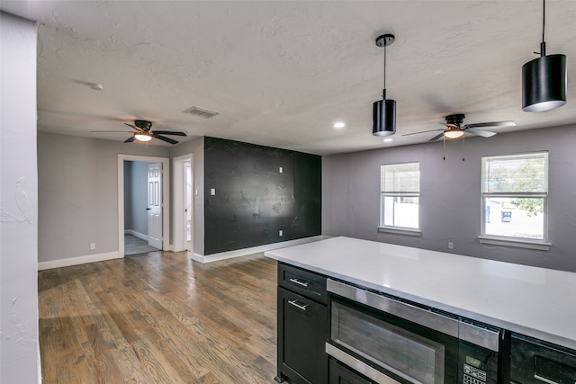 kitchen with ceiling fan, built in microwave, dark wood-type flooring, and hanging light fixtures