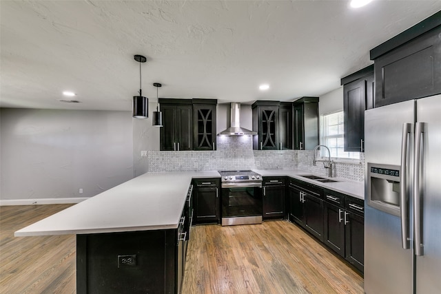 kitchen featuring light wood-type flooring, wall chimney exhaust hood, tasteful backsplash, appliances with stainless steel finishes, and sink