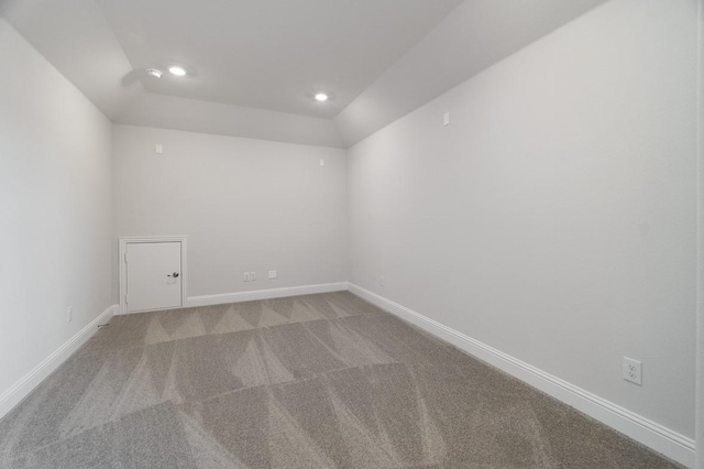 carpeted spare room featuring vaulted ceiling