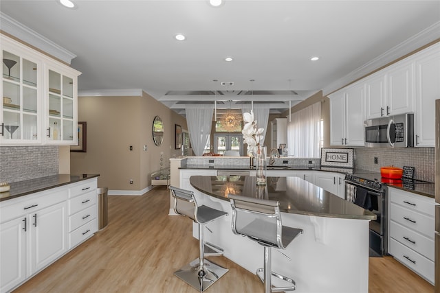 kitchen with white cabinetry, a kitchen bar, electric range, and light hardwood / wood-style flooring