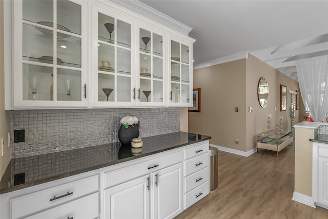 kitchen with light hardwood / wood-style flooring, white cabinets, ornamental molding, and tasteful backsplash