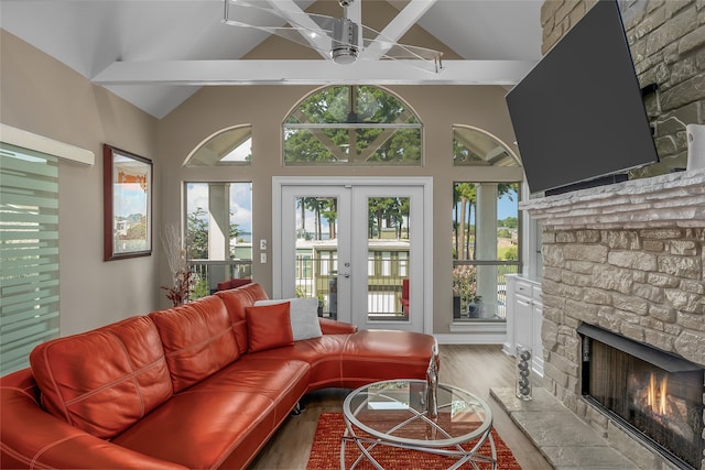 sunroom / solarium with ceiling fan, vaulted ceiling, a stone fireplace, and french doors