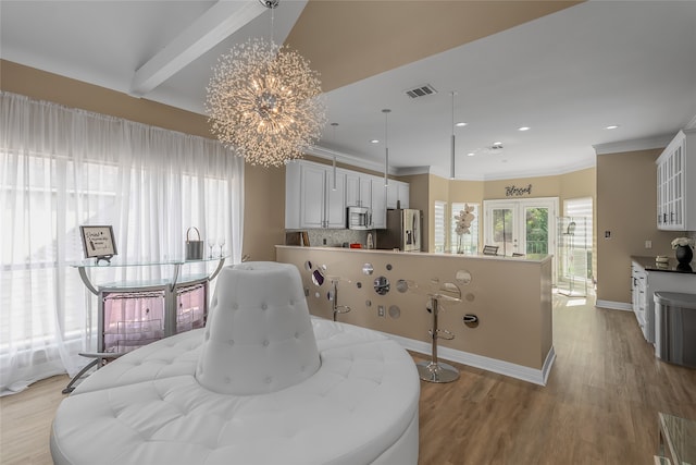 dining space with light hardwood / wood-style floors, a chandelier, and beamed ceiling