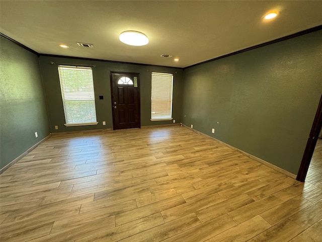 entryway with light wood-type flooring and crown molding