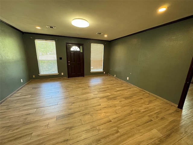 entryway with light wood-style floors, visible vents, crown molding, and baseboards