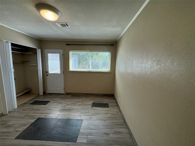 doorway featuring ornamental molding and a textured ceiling