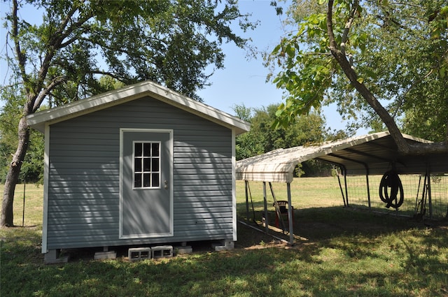 view of outdoor structure with a carport and a lawn