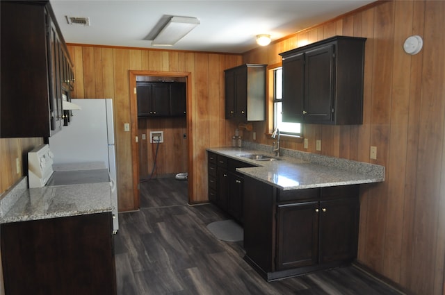 kitchen with wood walls, sink, range, dark wood-type flooring, and light stone counters