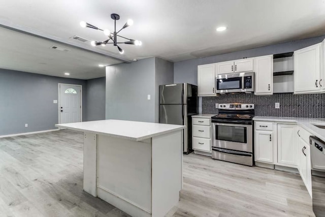 kitchen featuring appliances with stainless steel finishes, light hardwood / wood-style flooring, backsplash, white cabinetry, and a chandelier