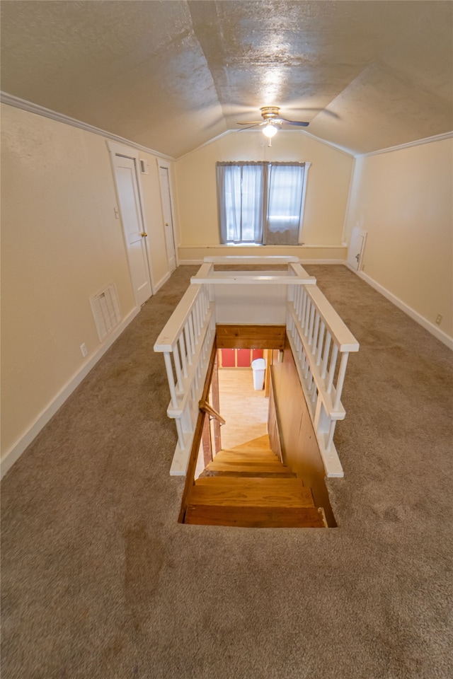 interior space with a textured ceiling, ceiling fan, vaulted ceiling, and carpet