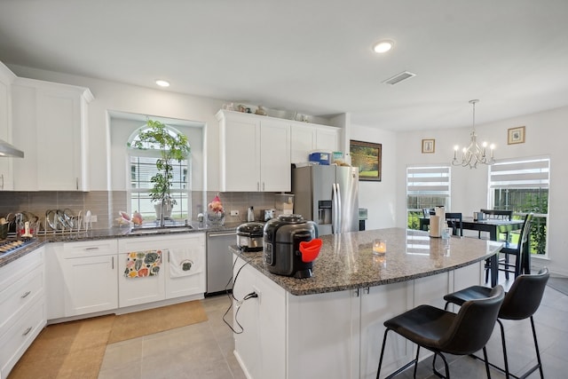 kitchen with light tile patterned floors, appliances with stainless steel finishes, a kitchen island, and backsplash