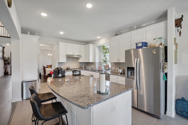 kitchen featuring backsplash, stainless steel fridge, white cabinets, and a kitchen island